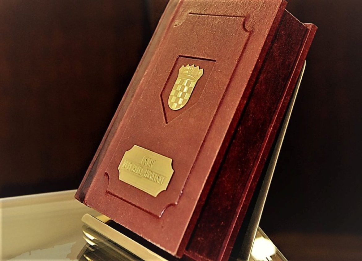 Red leather-bound award plaque with a gold crest and nameplate, angled on a display stand.