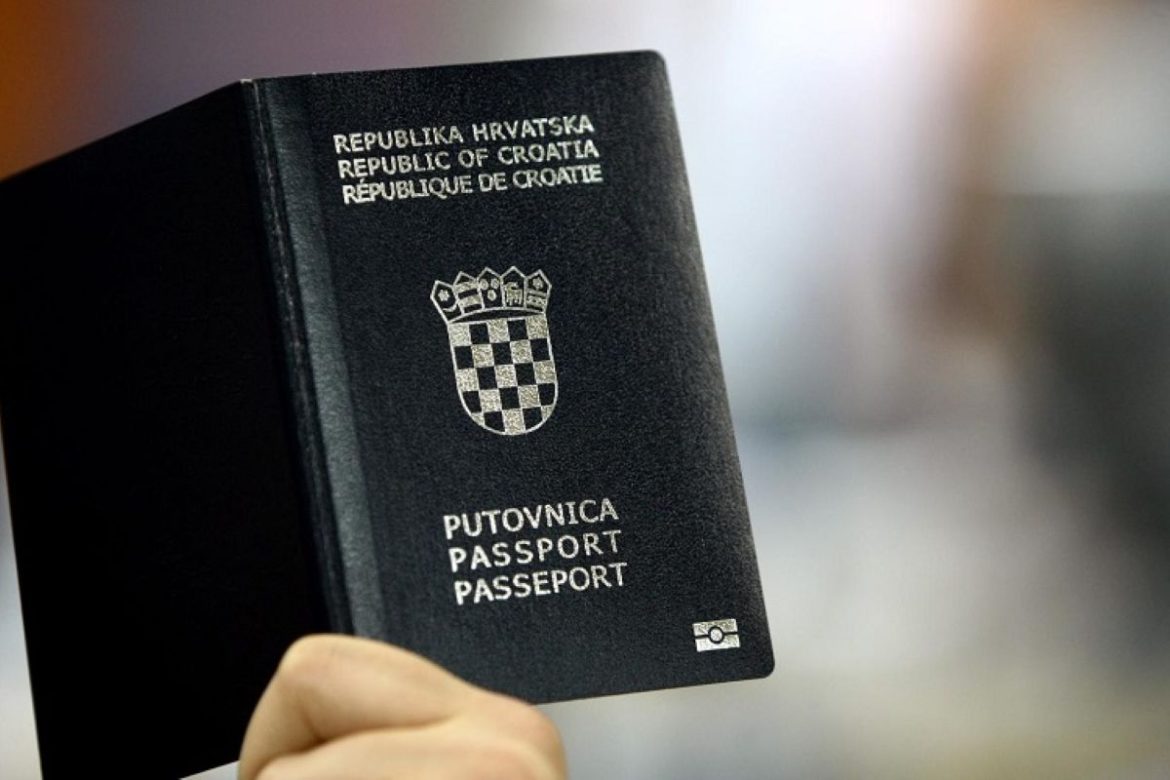 Close-up of a Croatian passport being held, showing the crest and text 'Republic of Croatia' on a dark cover.